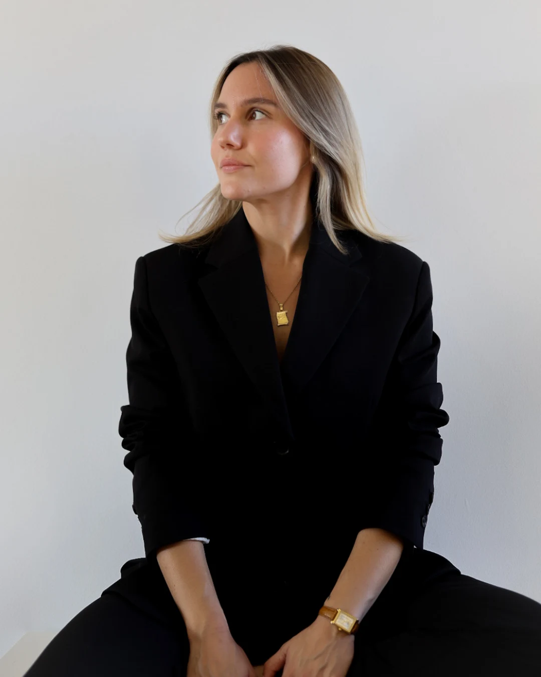 La creadora de Vega Studio, sentada con un traje negro en un estudio de luz natural